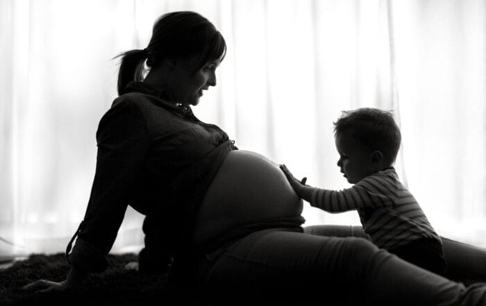 Junge ölt den Babybauch ein