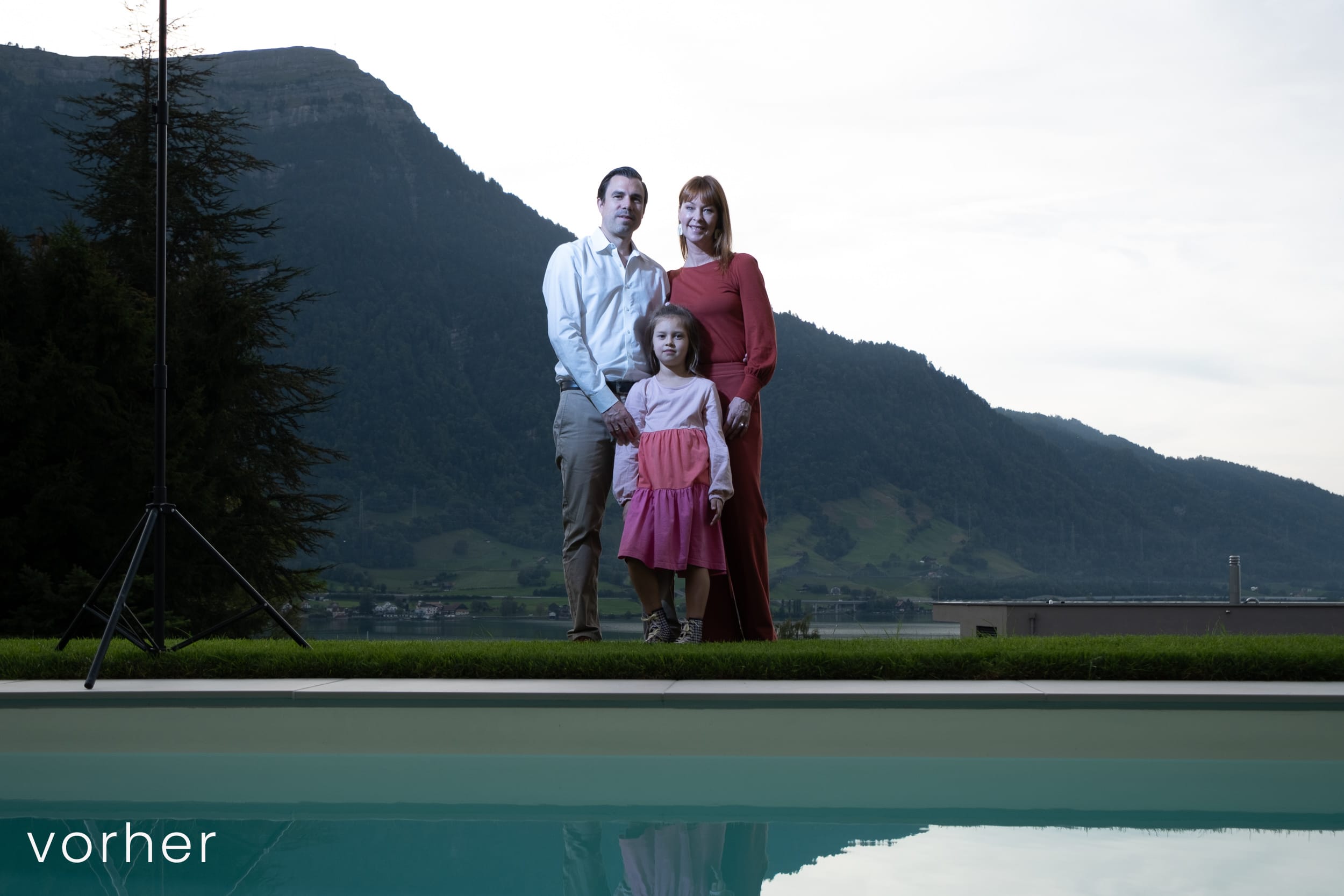 Familie steht hinter Pool mit Spiegelung und Sonnenuntergang hinter der Rigi.